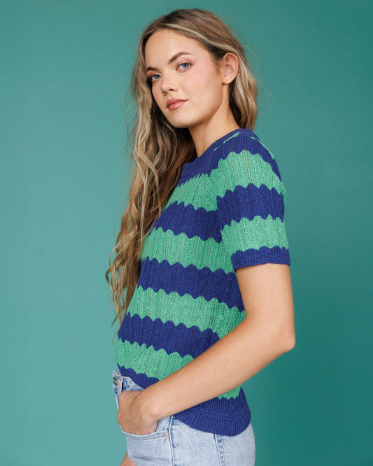 Woman wearing a blue and green striped sweater against a teal background