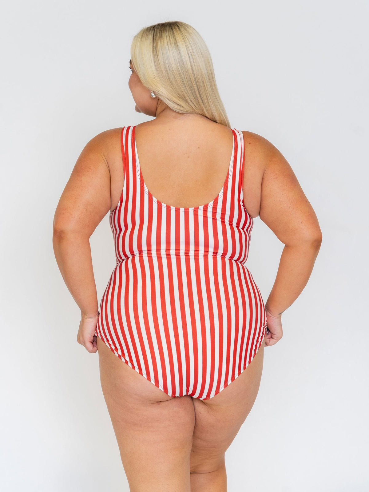 Person wearing a red and white striped swimsuit on a plain background