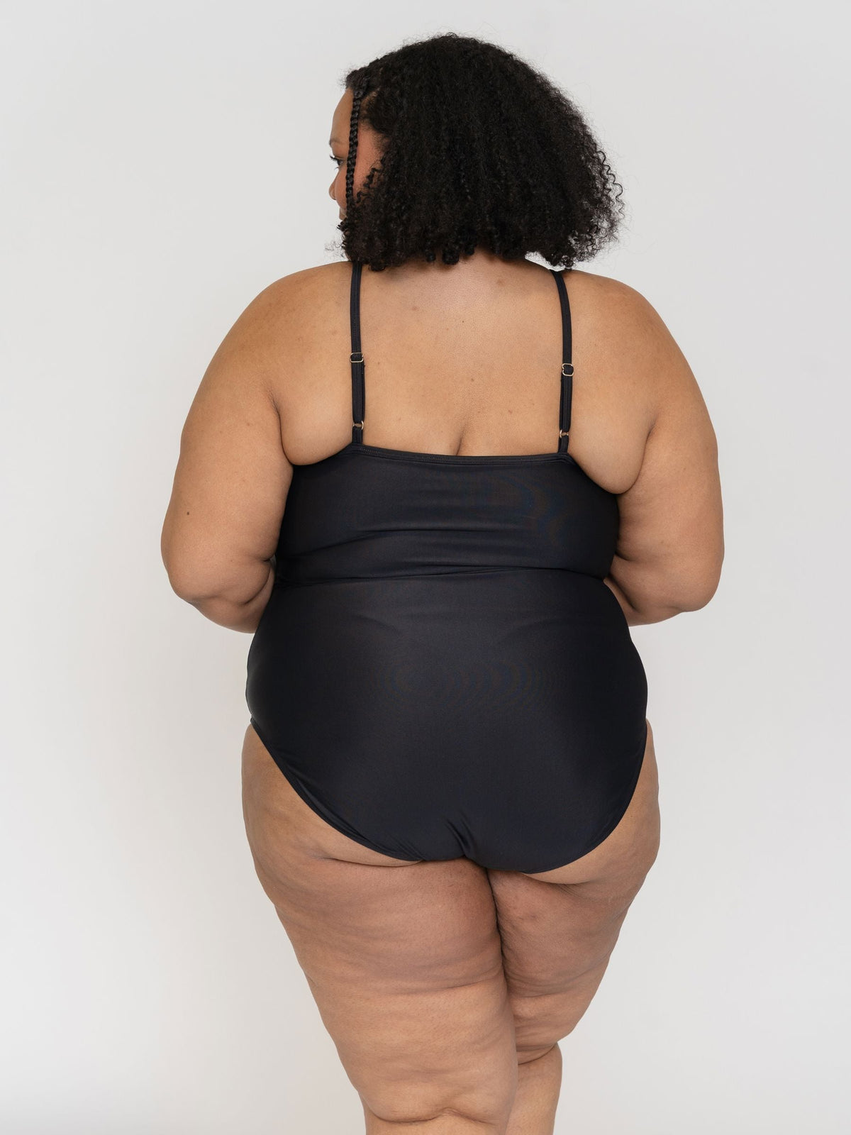 Person wearing a black swimsuit against a white background