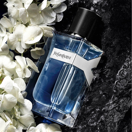 Blue Yves Saint Laurent Y Eau de Toilette bottle with white flowers on a dark background
