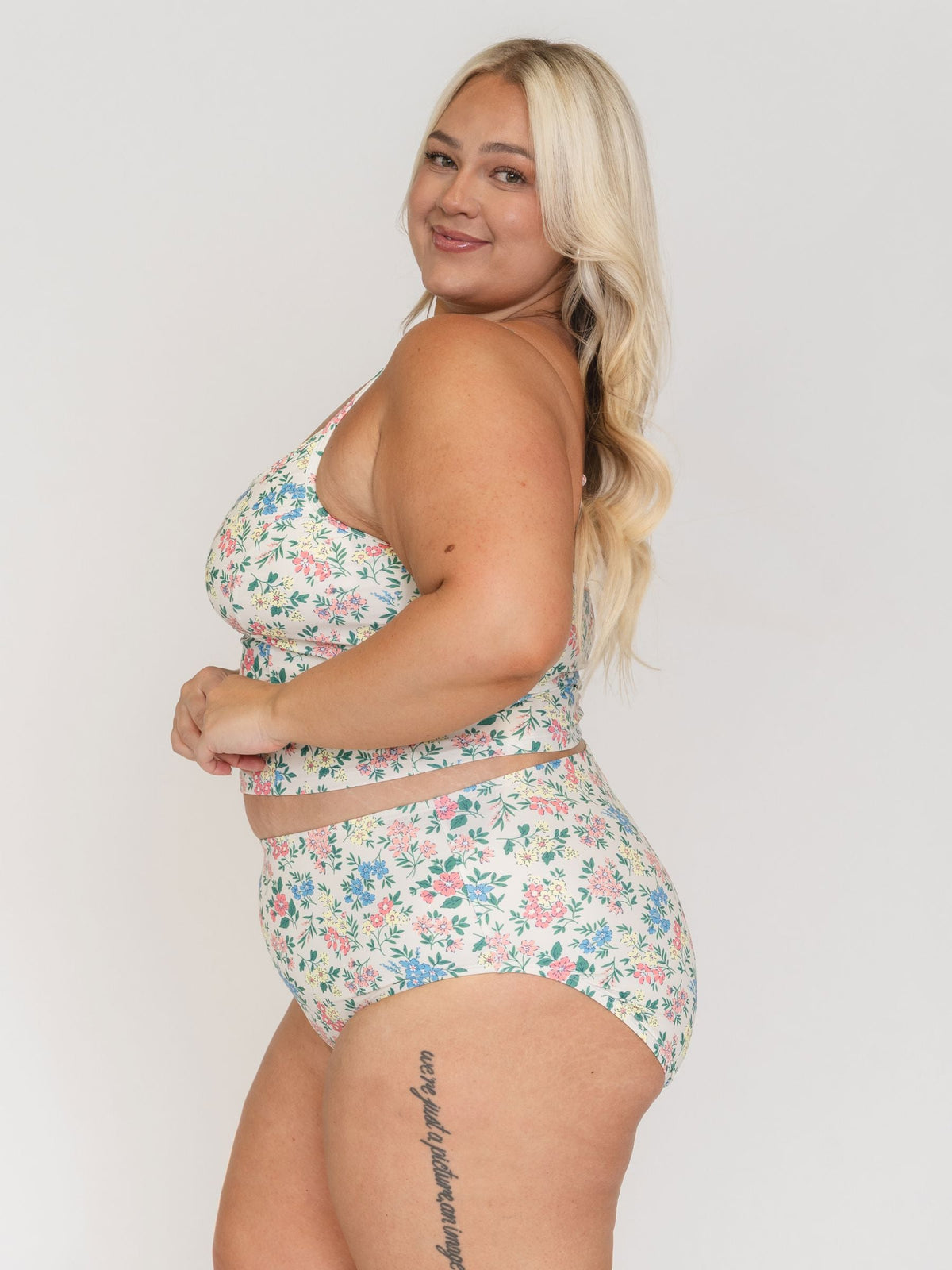 Woman wearing a floral two-piece swimsuit against a plain background