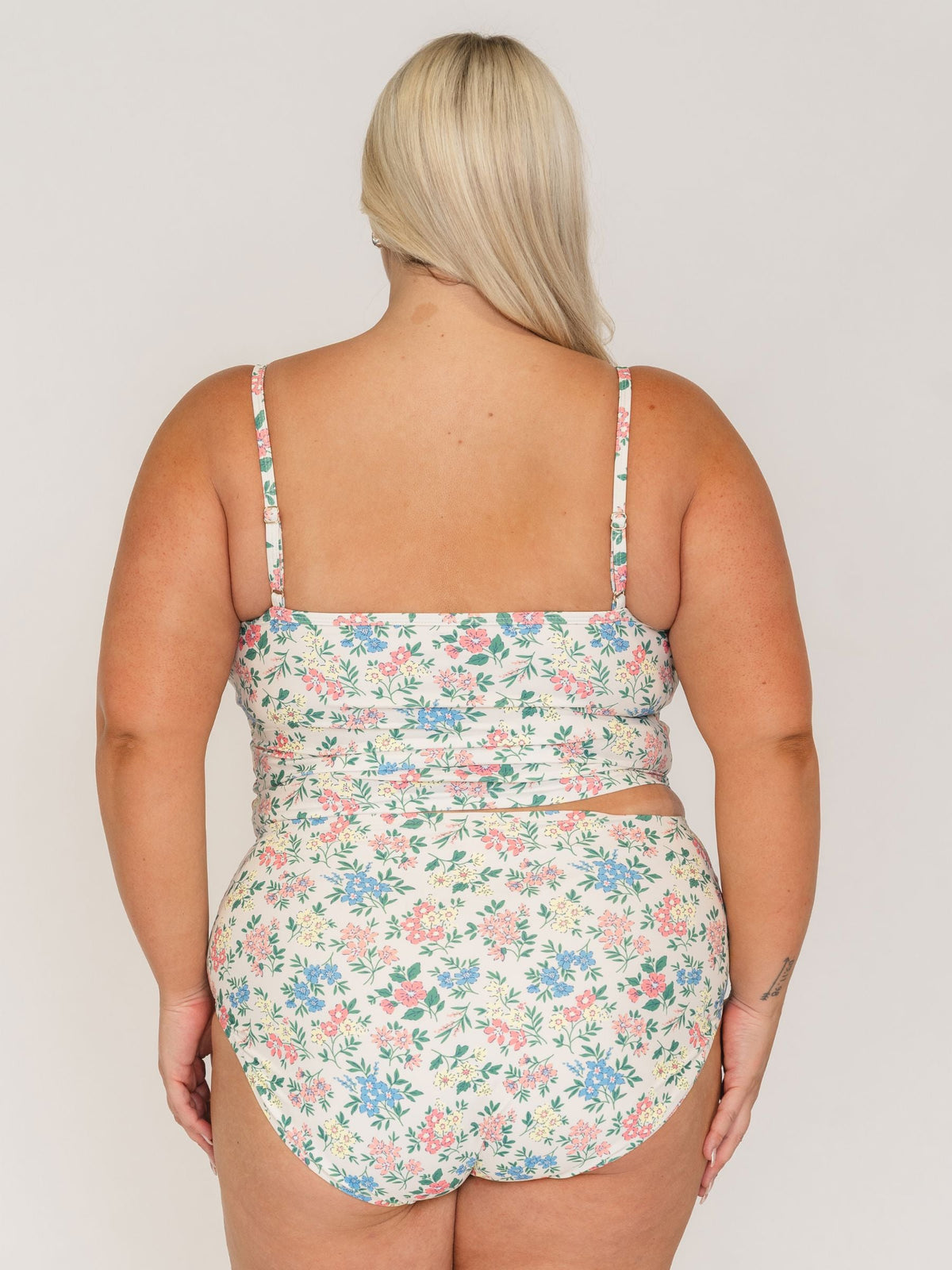 Woman wearing a floral swimsuit against a plain background