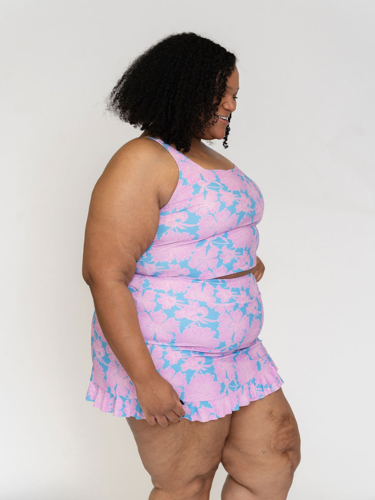 Woman wearing a pink and blue floral dress against a white background