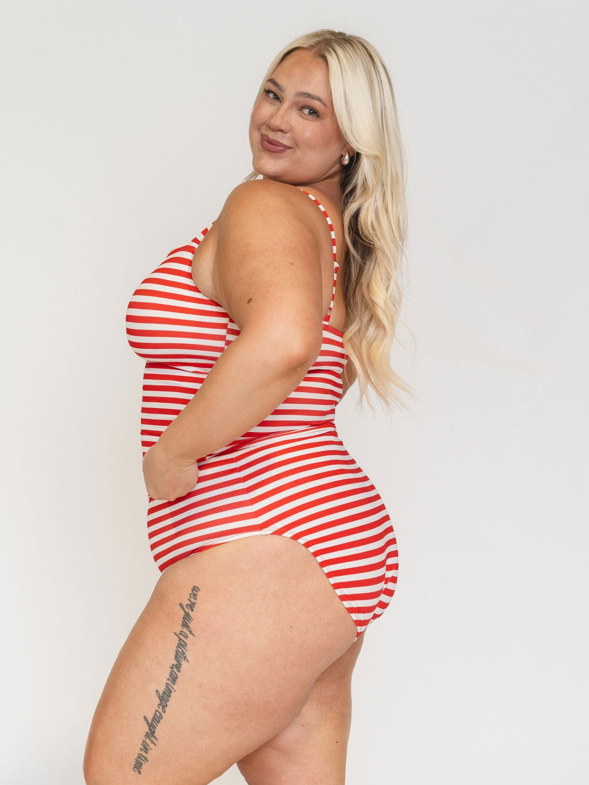 Woman wearing a red and white striped swimsuit on a plain background