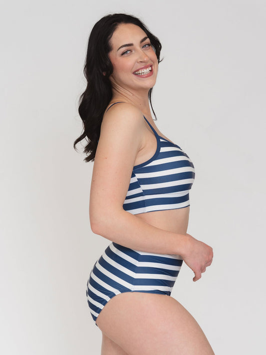 Woman wearing a blue and white striped swimsuit on a plain background