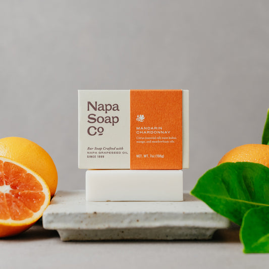 Napa Soap Co. soap bar with packaging on a gray surface with oranges and leaves.