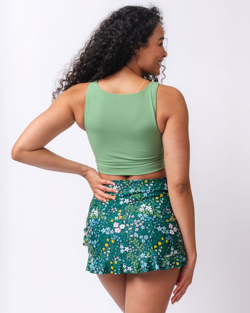 Woman wearing a green crop top and floral skirt on a white background