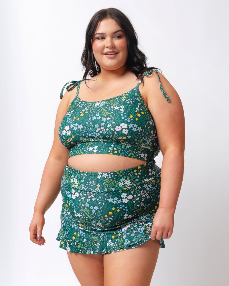 Woman wearing a green floral two-piece swimsuit on a white background