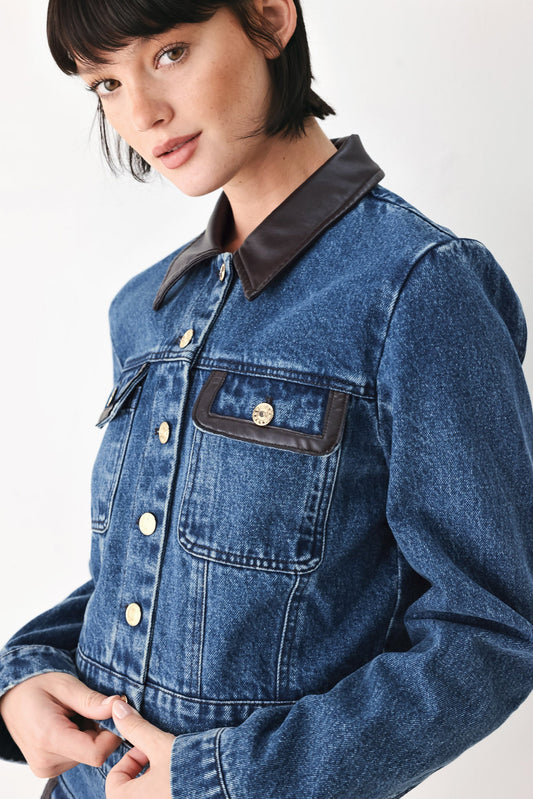 Cropped washed denim jacket with brown faux leather pocket trim and long sleeves.