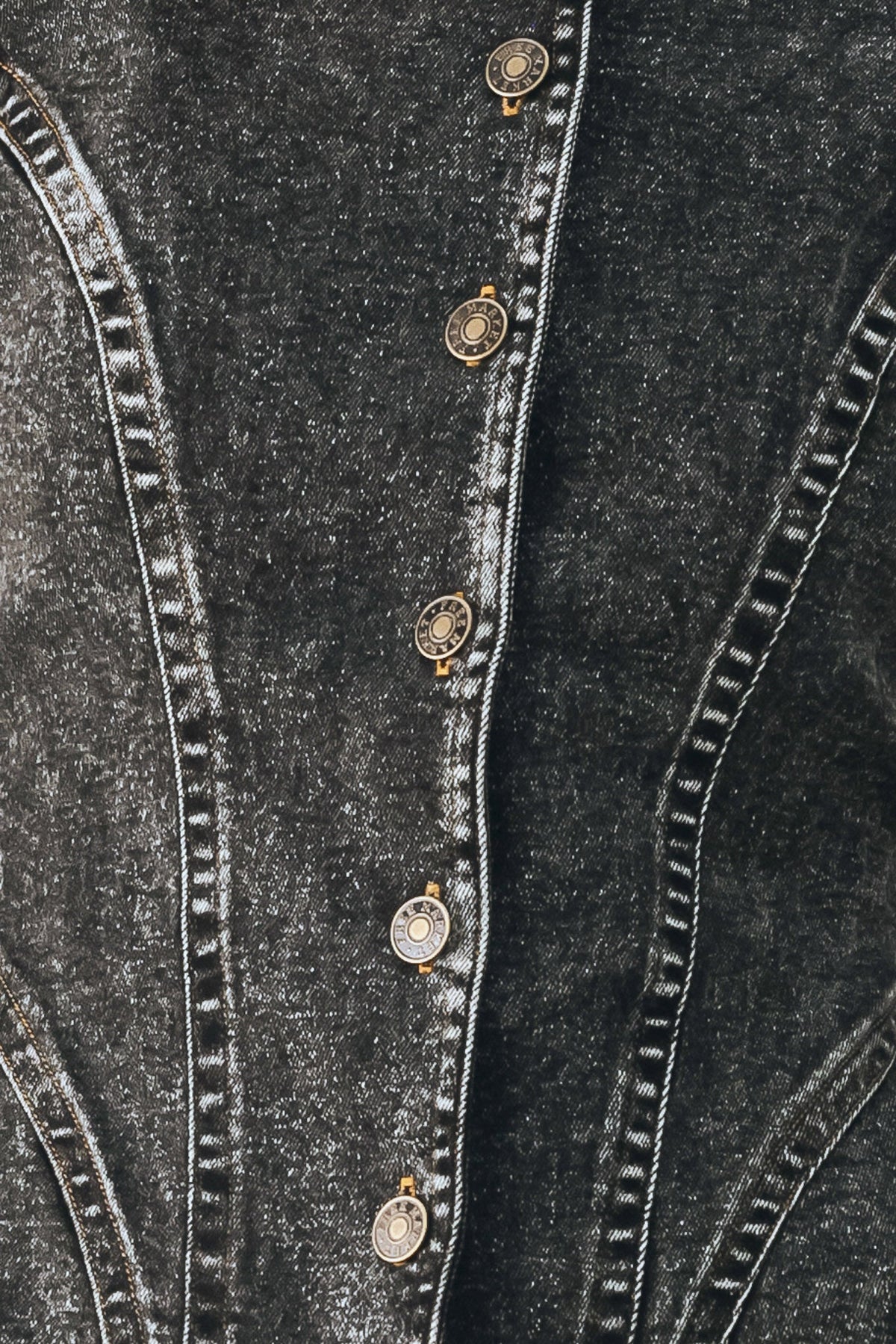 Close-up of a dark gray denim jacket showing the buttoned front closure with decorative round metal buttons and contrast stitching.