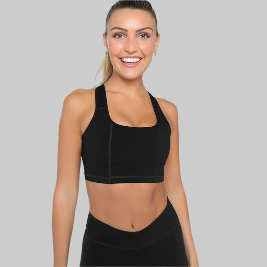 Woman wearing a black sports bra and leggings on a gray background