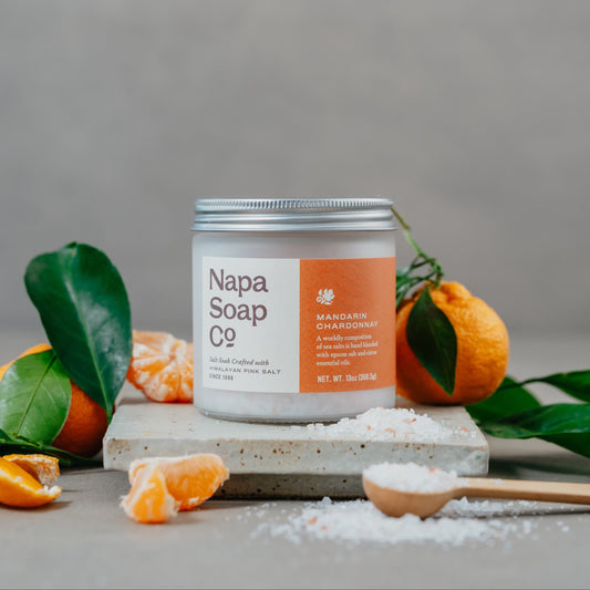 Mandarin Chardonnay bath salt soak with mandarin oranges and loose salt on a gray background