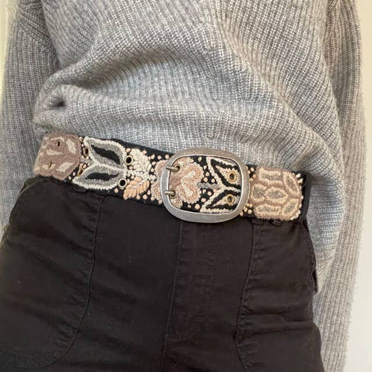 Person wearing a decorative belt with intricate patterns on a neutral background