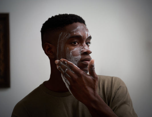 Man applying cream to his face against a plain background