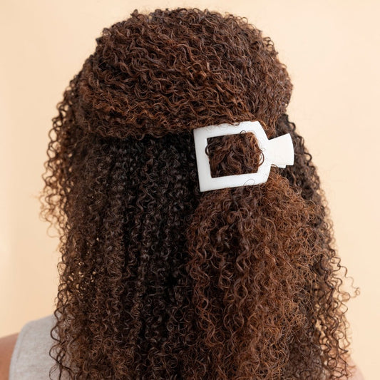 Curly hair with a white hair clip on a beige background