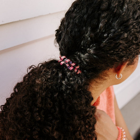 Close-up of curly hair tied in a ponytail with a pink TELETIES coil hair tie