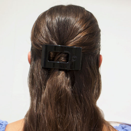 Person with a black hair clip in their hair against a white background