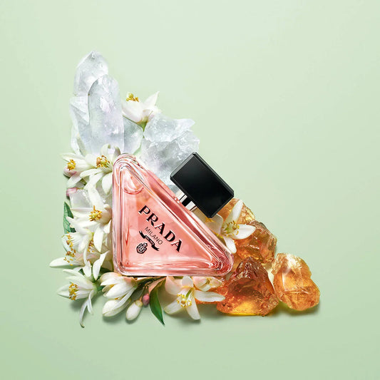 Prada perfume bottle with flowers and crystals on a light green background