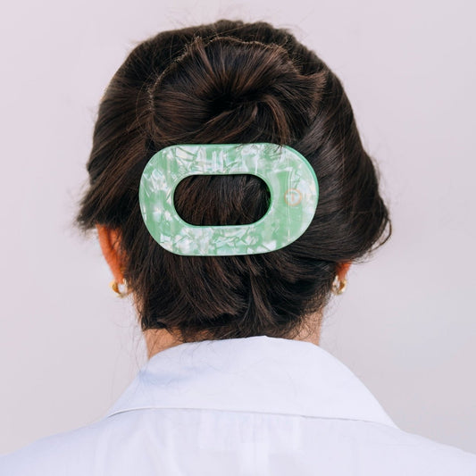 Person with a floral-patterned green hair clip in their hair against a plain background