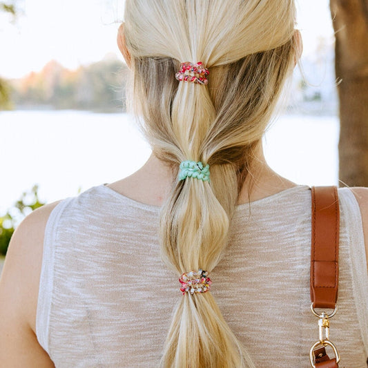 Person with a ponytail using colorful hair ties outdoors
