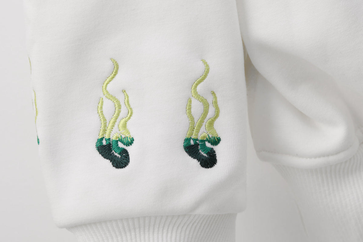 Embroidered green and black designs on a white garment