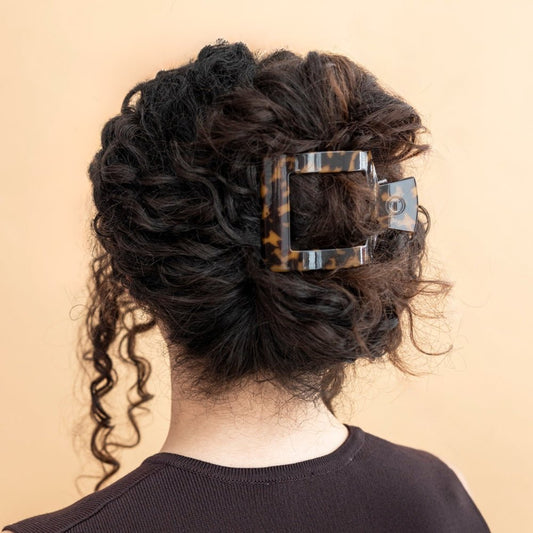 Person with styled hair featuring a decorative hair clip on a beige background