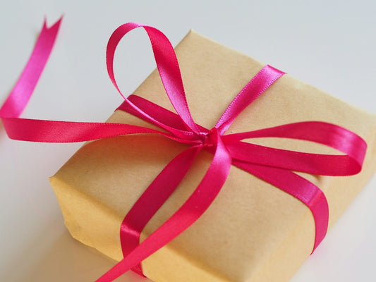 A brown gift box tied with a pink ribbon