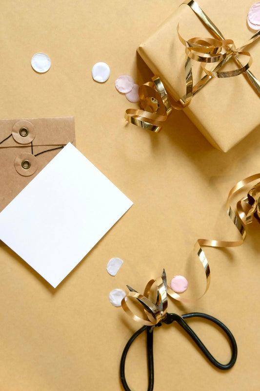 A gift box with ribbon, a card, and confetti