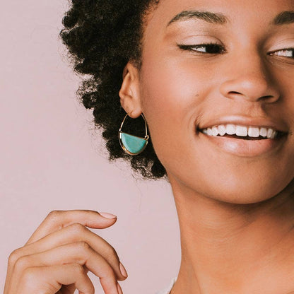 Woman wearing a turquoise earring against a pink background