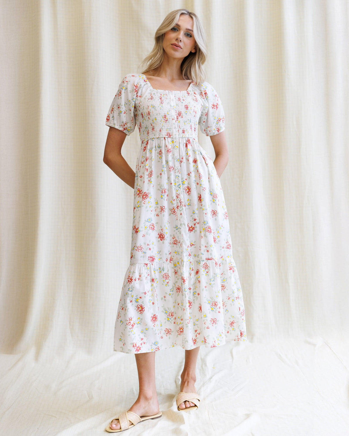 Woman wearing a floral dress against a white curtain background