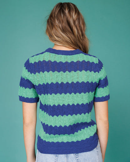 Person wearing a blue and green striped sweater against a teal background
