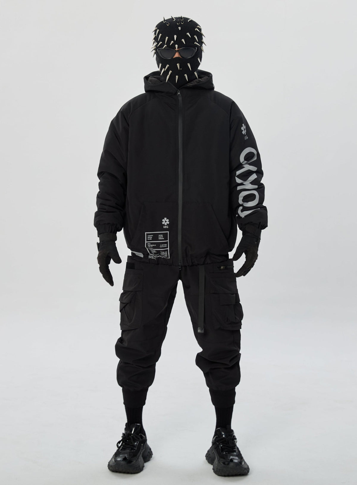 Person wearing a black outfit with text on sleeves against a white background
