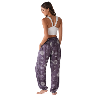 Woman wearing a white sports bra and purple patterned pants on a white background