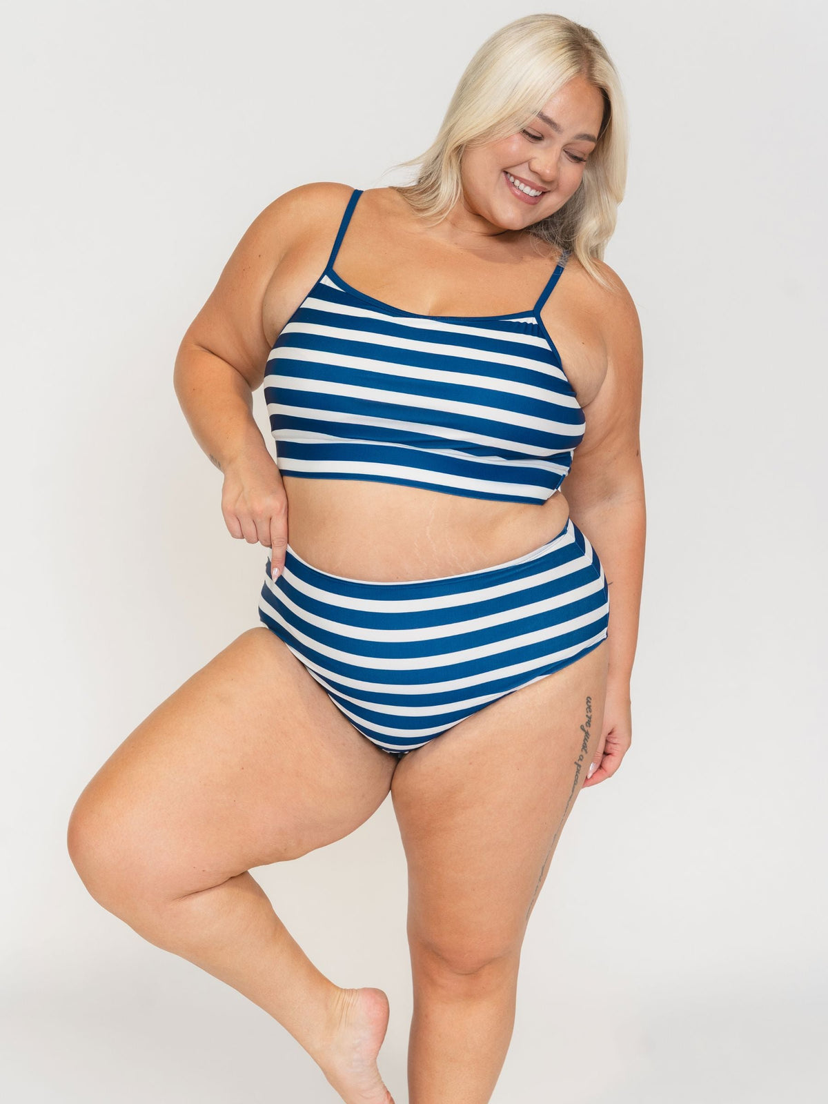 Woman wearing a blue and white striped swimsuit on a plain background