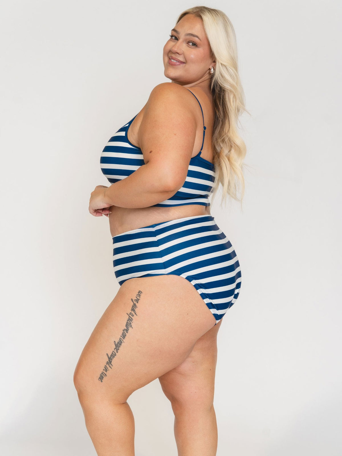 Woman wearing a blue and white striped swimsuit on a plain background