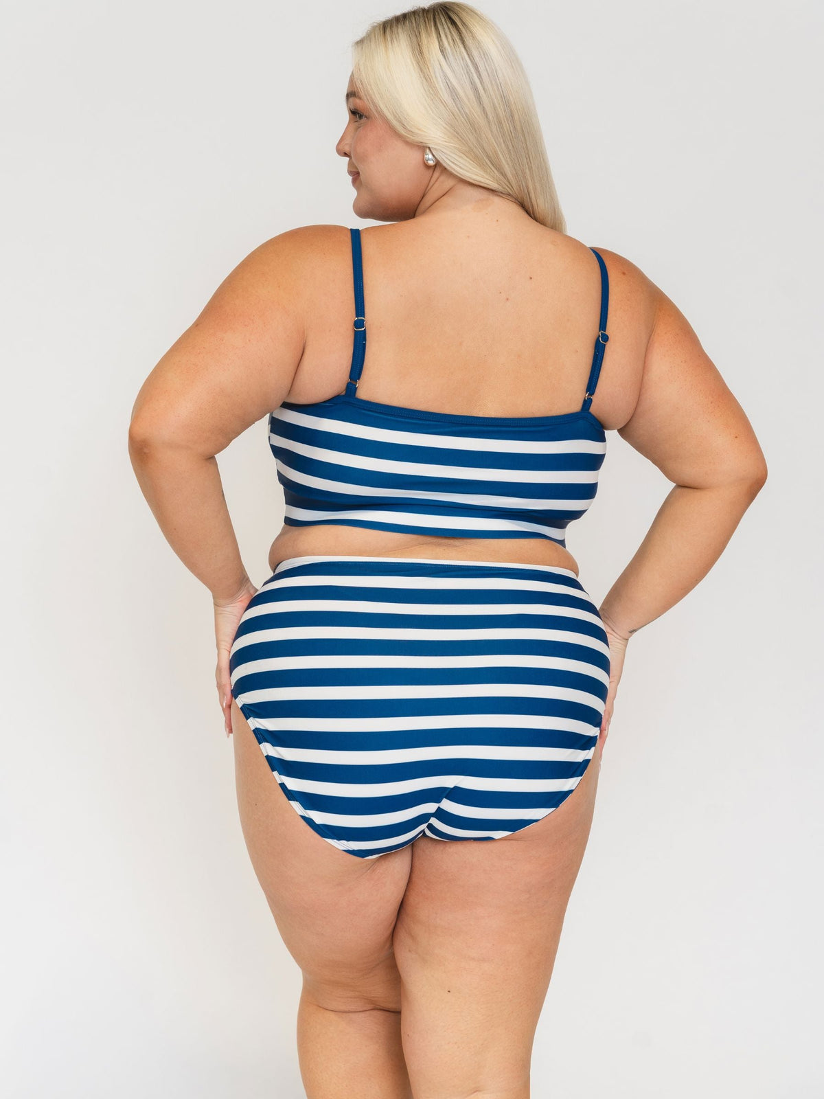 Woman wearing a blue and white striped swimsuit on a plain background