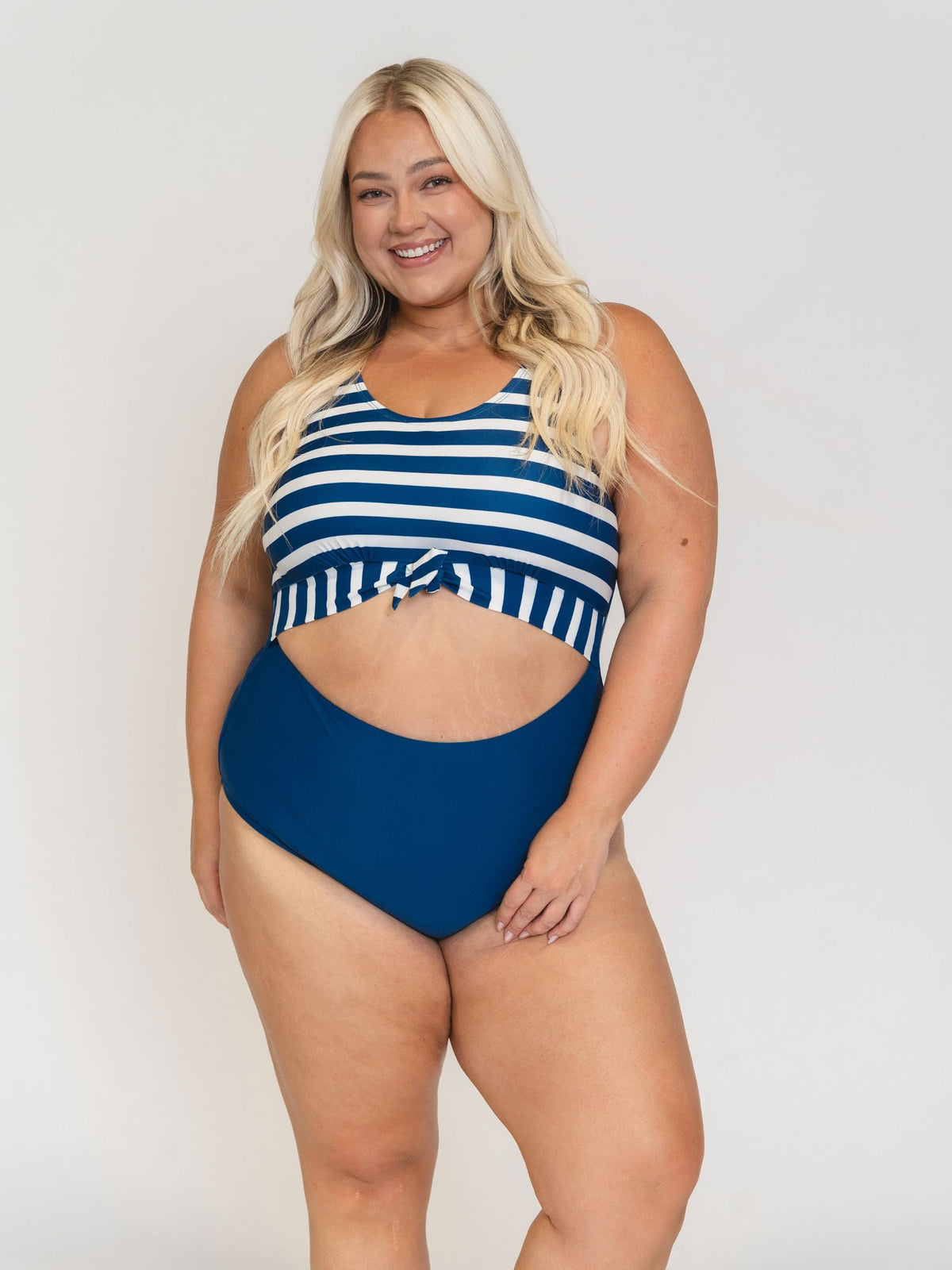 Woman wearing a blue and white striped swimsuit on a plain background