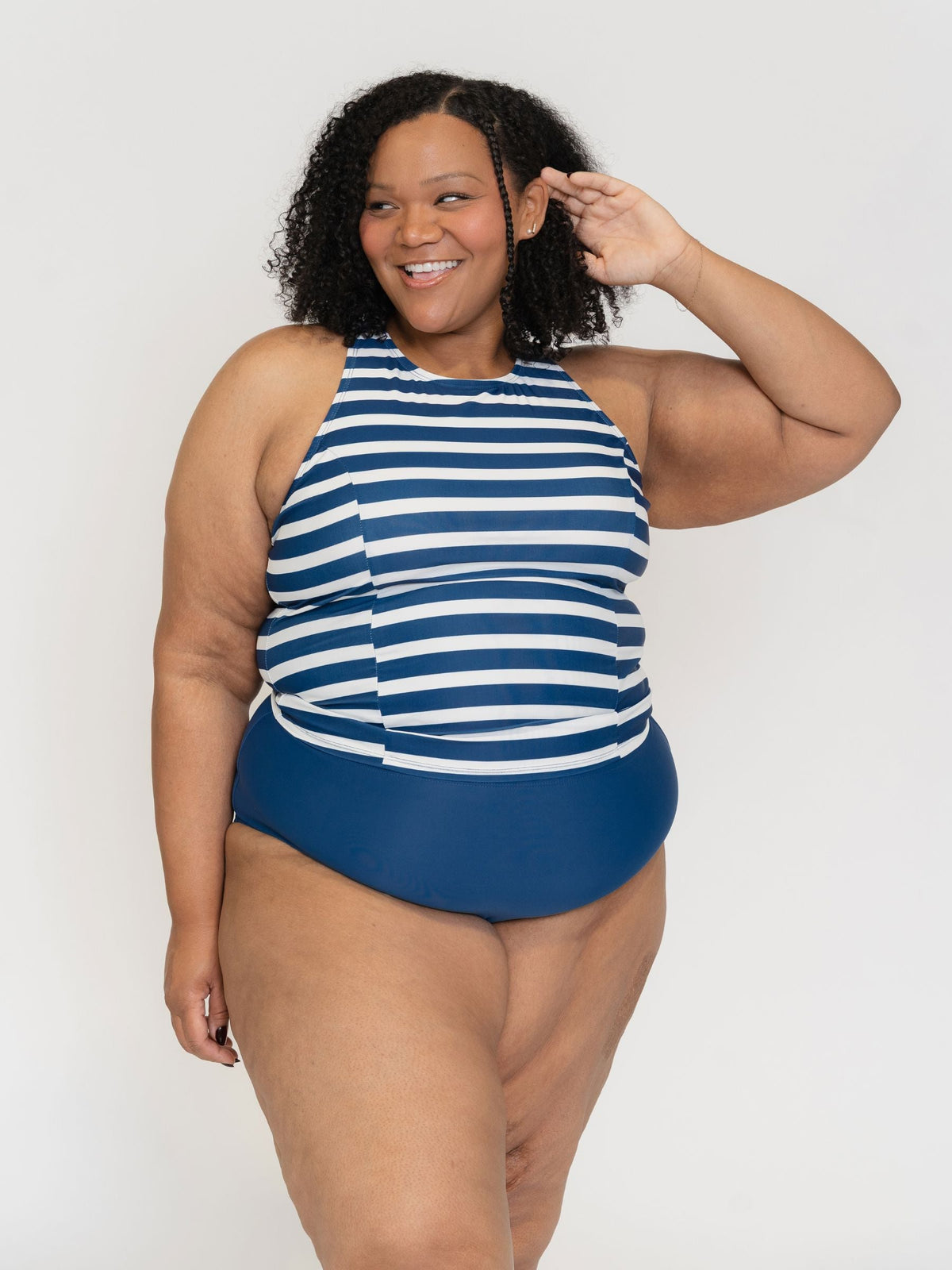 Woman wearing a blue and white striped swimsuit against a plain background