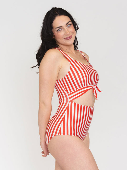 Woman wearing a red and white striped swimsuit on a plain background