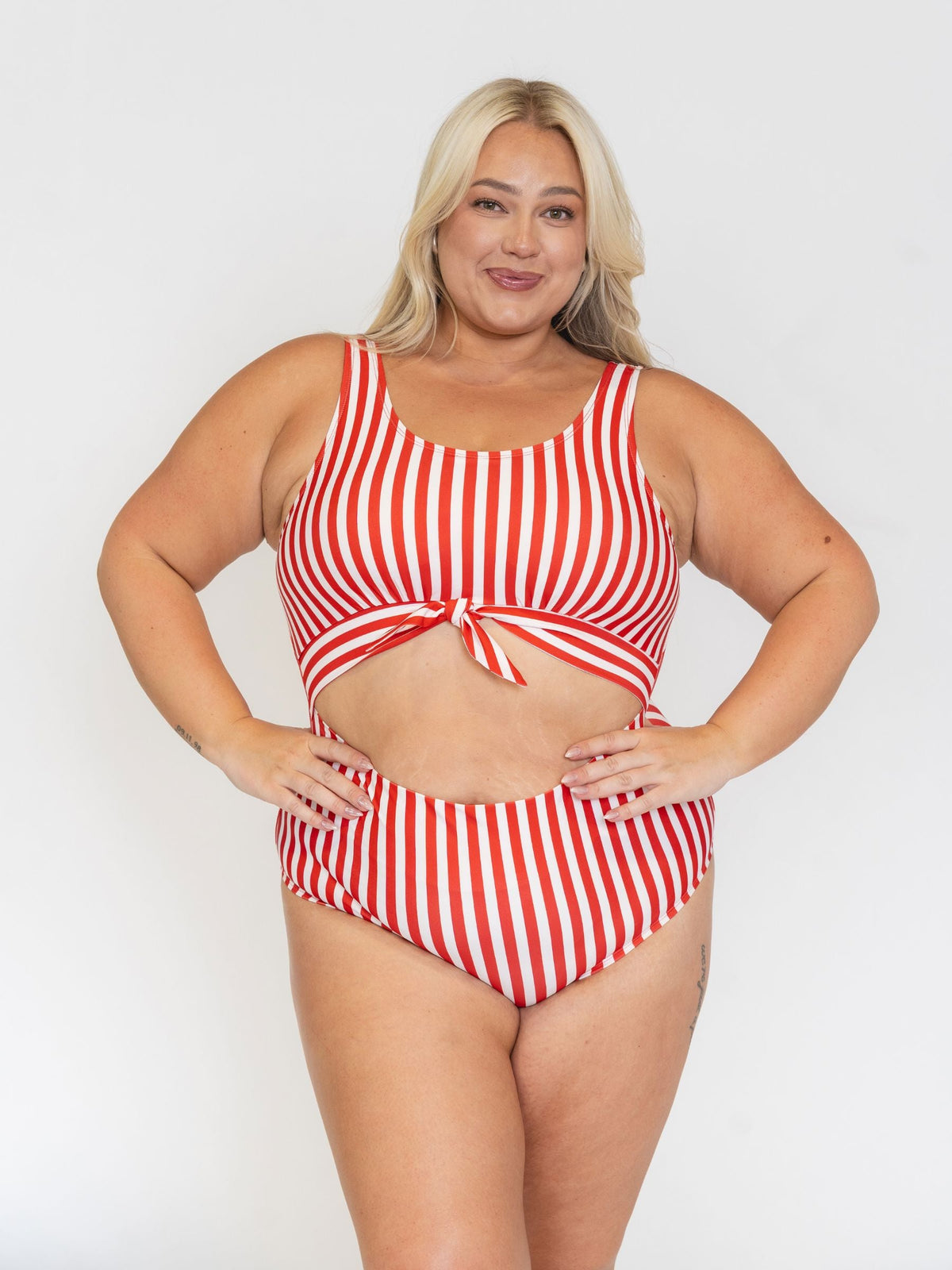 Woman wearing a red and white striped bikini set on a plain background