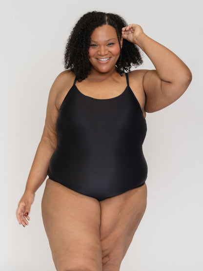 Woman wearing a black swimsuit against a white background