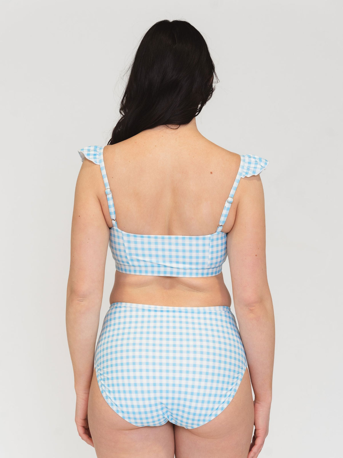 Woman wearing a blue and white checkered bikini set on a plain background