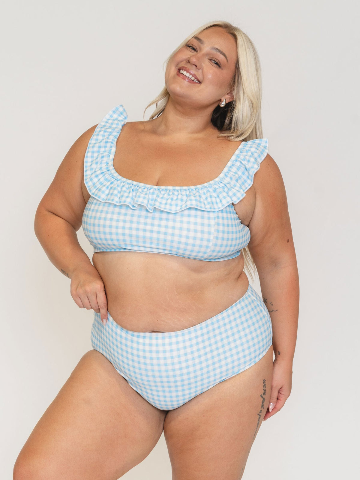 Woman wearing a blue and white checkered bikini set against a plain background