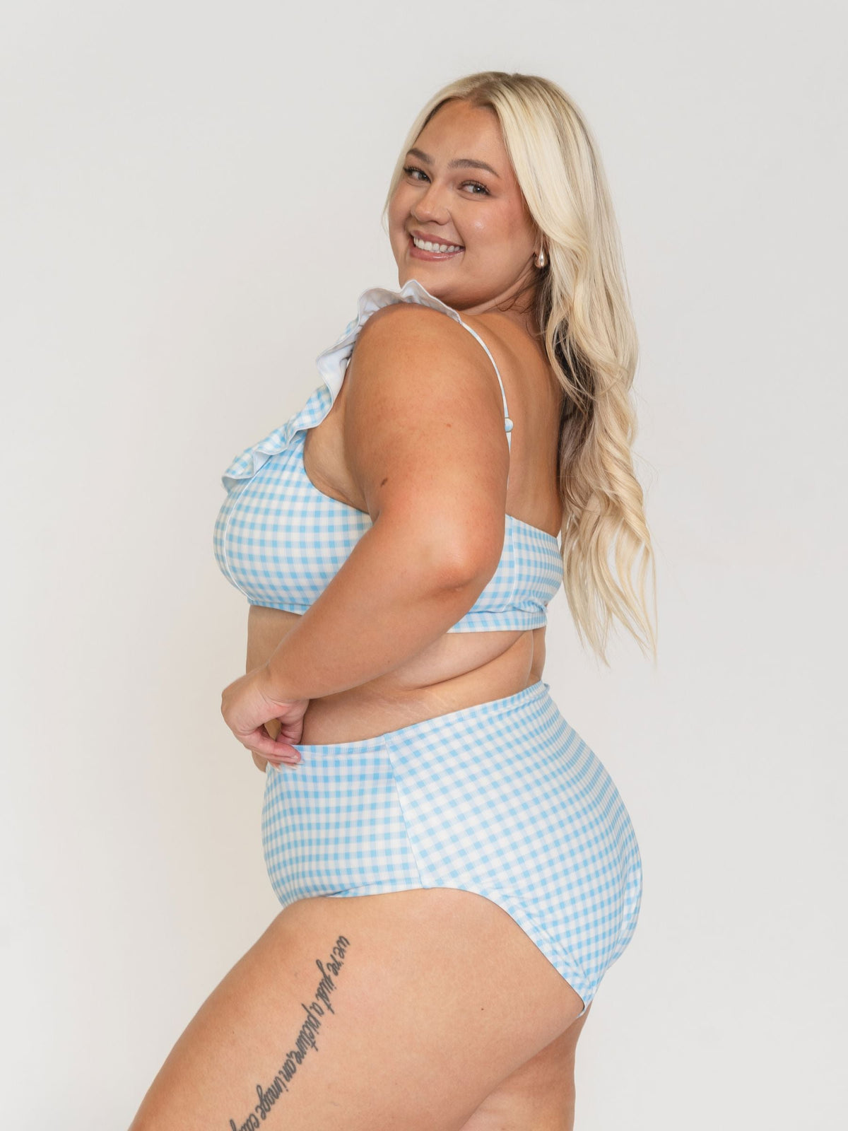 Woman wearing a blue and white checkered bikini set on a plain background
