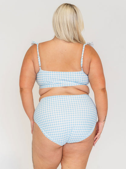 Woman wearing a blue and white checkered bikini set on a plain background