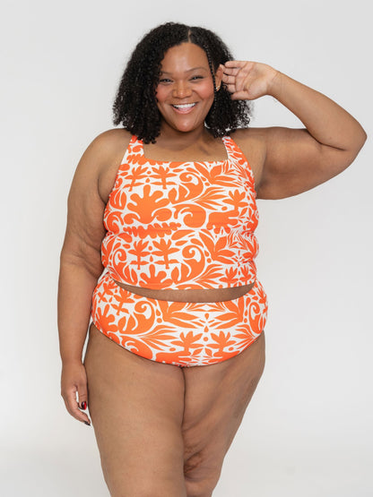 Woman wearing an orange and white patterned swimsuit on a white background