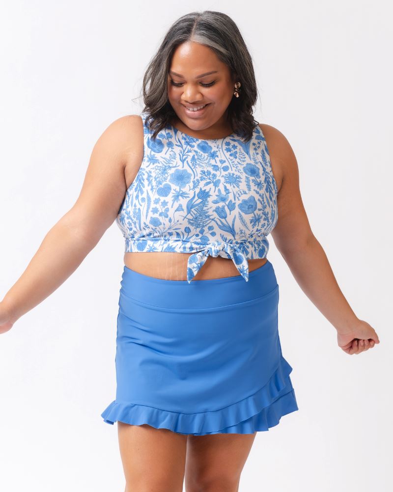 Woman wearing a blue floral top and blue skirt on a white background