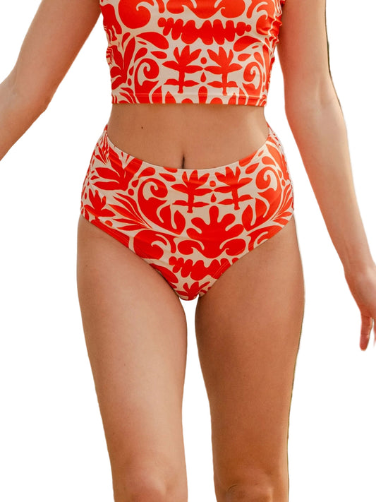 A model wearing a two-piece bikini with a vibrant red and cream floral damask pattern, shown from the chest down against a solid white background.