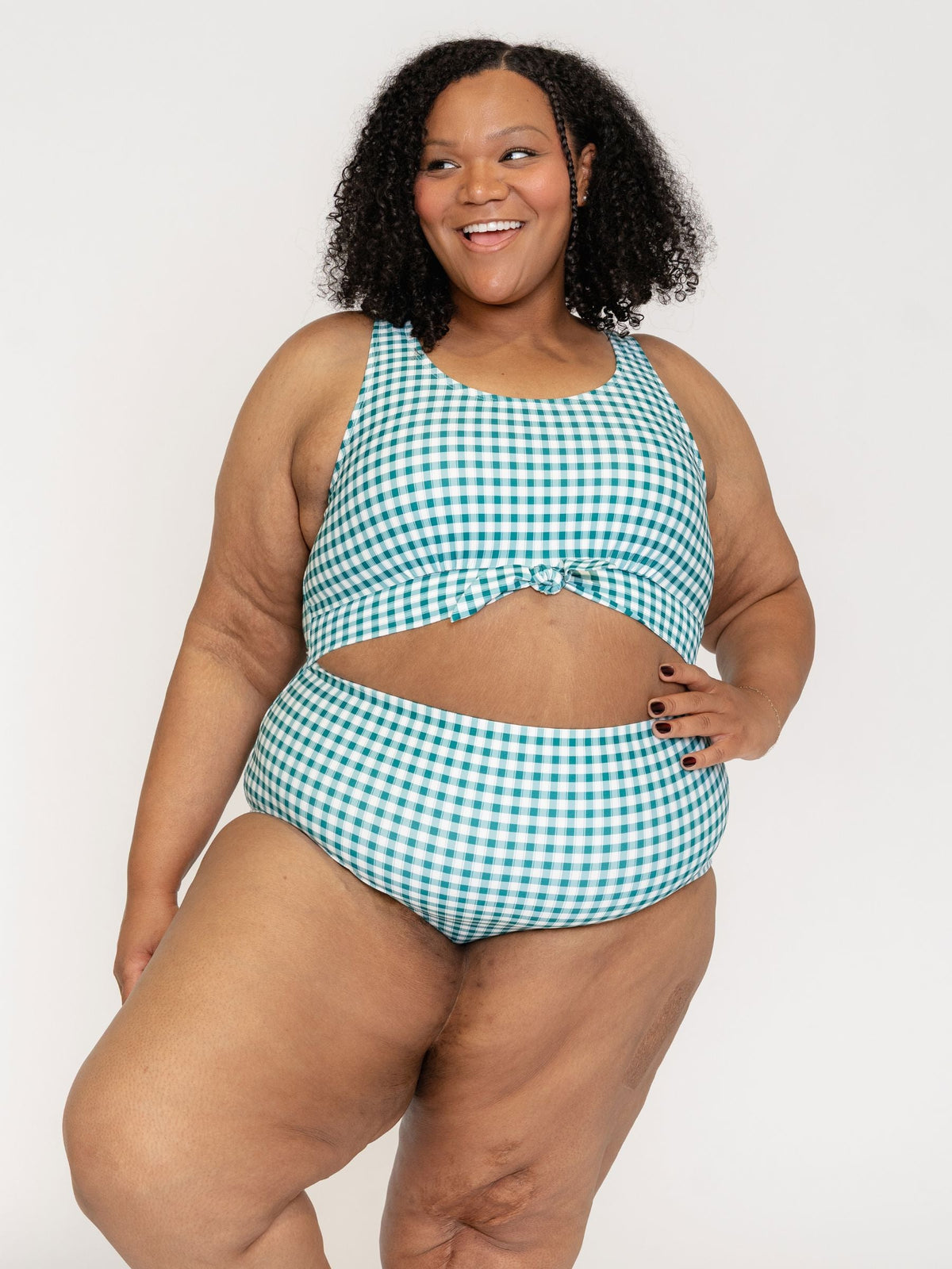 Woman wearing a green and white checkered swimsuit on a plain background