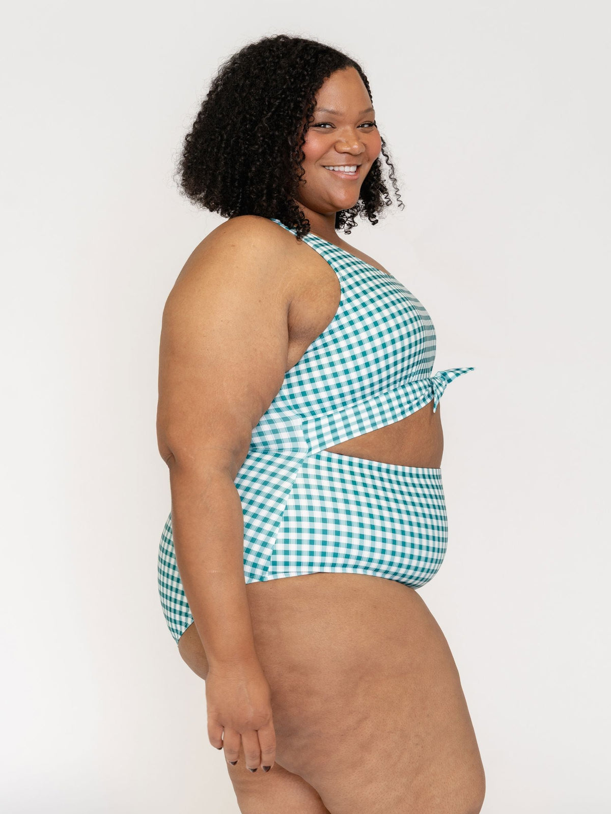 Woman wearing a green and white checkered swimsuit against a white background